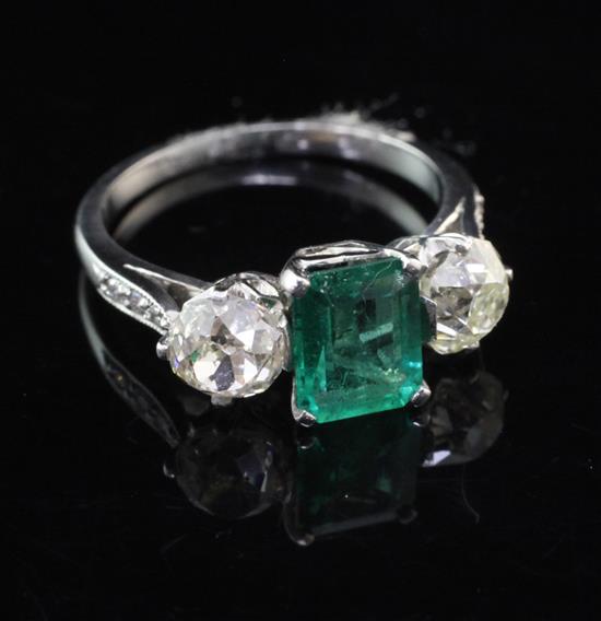 A platinum, emerald and diamond three stone ring, with diamond set shoulders, size N.